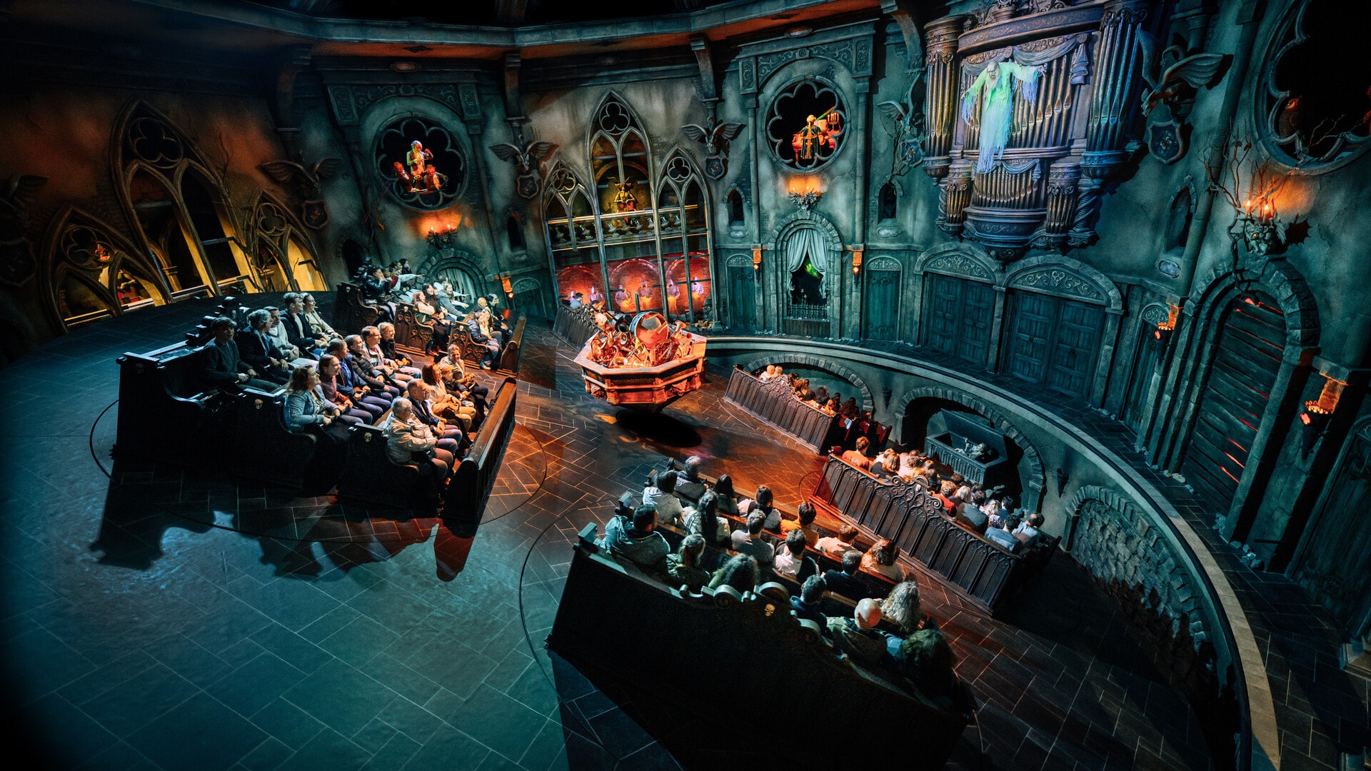 Interieur van de attractie Danse Macabre in een donkere setting met vijf koorbanken die op een gekantelde draaischijf staan.